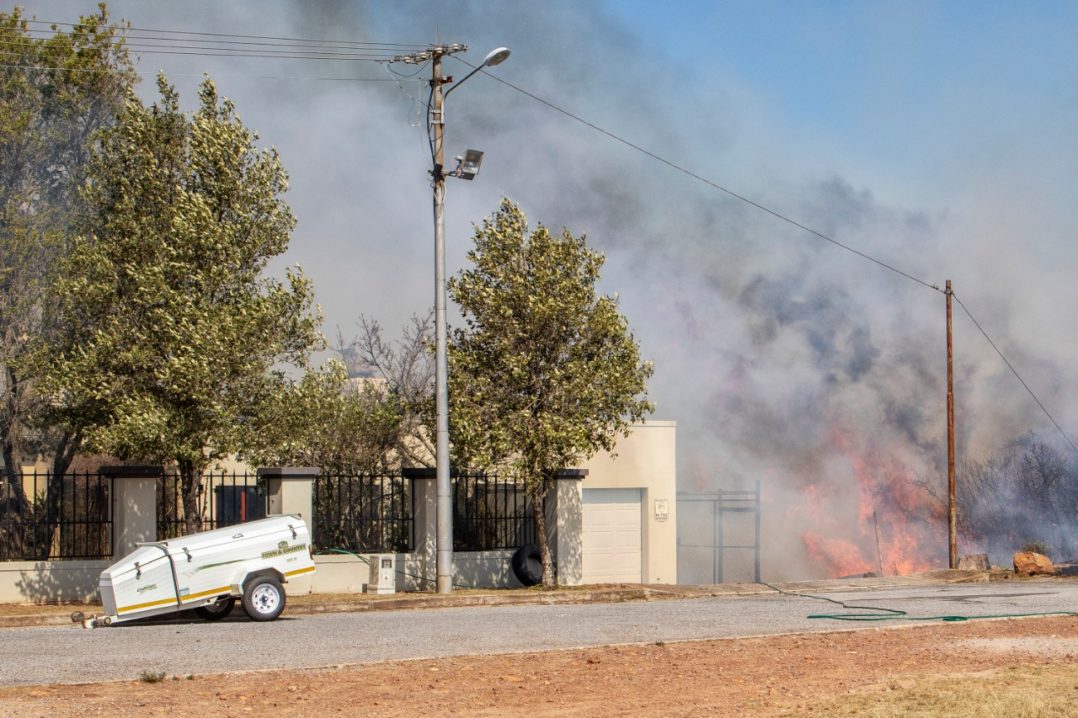 A Hill 60 resident battles flames behind his property during a fire on the western commonage on Thursday 24 September.